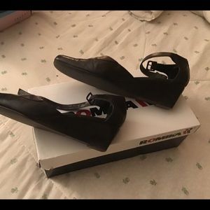 Black leather wedge shoes, strap fastens around ankle.